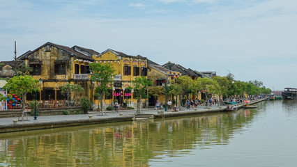 Fototapeta na wymiar AERIAL: Flying towards an idyllic riverside avenue in a tranquil Vietnamese town