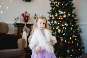 Lovely girl in purple dress in the background of Christmas decorations.