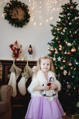 Lovely girl in purple dress in the background of Christmas decorations.