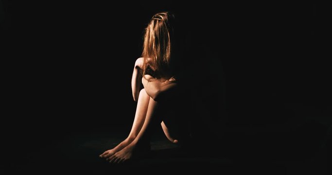 Nude woman in dark room. Abuse and depression concept.