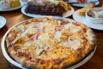 Fresh pizza with cheese pineapple and mushrooms on wooden table