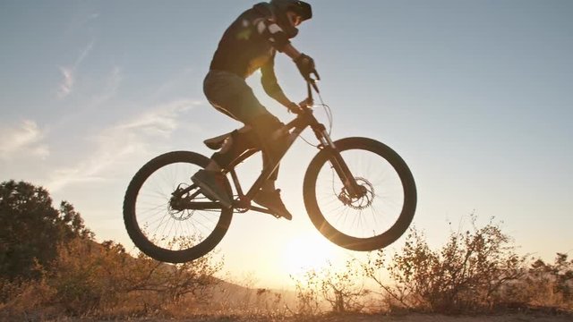 Cool mountain biker jumping at sunset, speeding up the trail, rushing down off road. Getting away from it all - activity, extreme