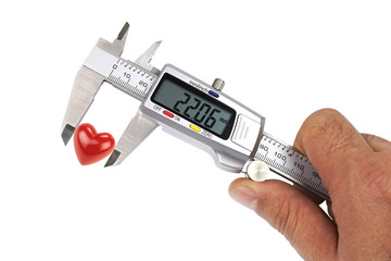 Digital caliper and red heart shape, conceptual image.