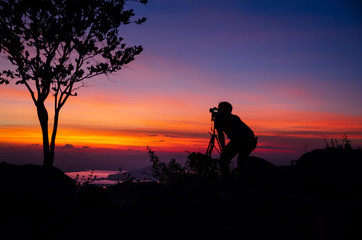 Silhouette Young man photographer taking nature photo on PhraYa Dern Thong mountain landscape.province Lopburi.Thailand. tourist photographe shooting dslr camera on tripod