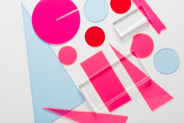 Figuras geométricas cuadrados, triángulos y círculos en color azul y rosa sobre fondo blanco