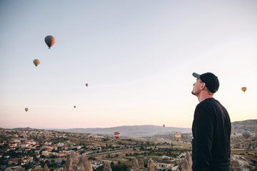 A man in solitude admires a beautiful view of the flying balloons in Cappadocia in Turkey.