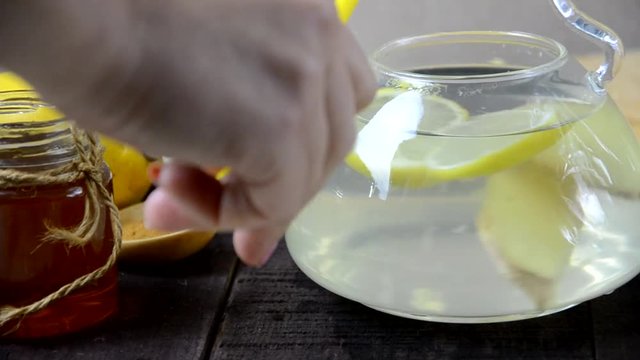 put turmeric honey hot water in a teapot to make a healthy drink. Teapot of ginger tea with honey and lemon on wooden table. Cup of ginger tea with honey and lemon on wooden table