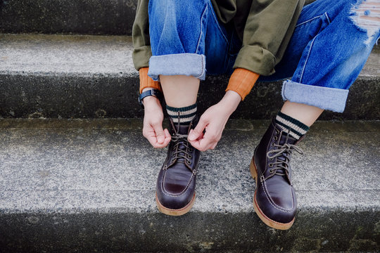 Fashion and Cloth for Autumn and Winter Season. Croped image for Jeans, Shoes and Sock. A Hipster Woman Tie Shoe laces while Sitting on Staircase