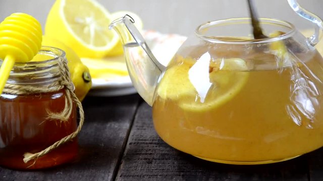 put turmeric honey hot water in a teapot to make a healthy drink. Teapot of ginger tea with honey and lemon on wooden table. Cup of ginger tea with honey and lemon on wooden table