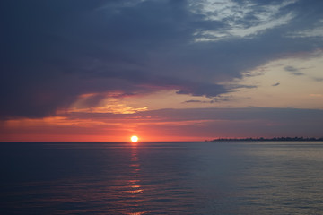Naklejka premium Amazing sunset on the ocean. View of dramatic cloudy sky and reflection of the sunlight on water.