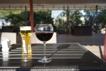 A glass of red wine on the table in a summer cafe on a blurred background with a glass of beer