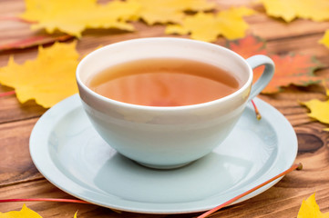 Cup of tea on the table with autumn leaves.