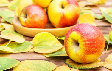 Ripe apples on the table with autumn leaves.