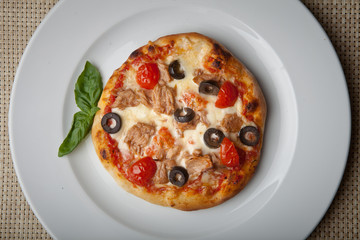 tomatoes and olives pizza on a white plate
