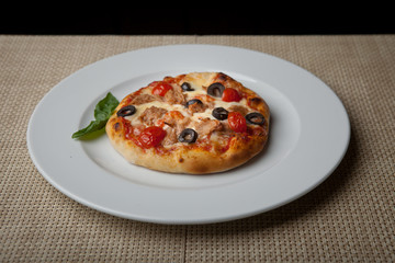 tomatoes and olives pizza on a white plate