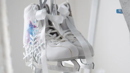 Pair of white figure skates with silvver snowflake hangs on decorated Christmas stepladder. New year concept