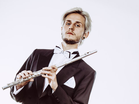 Male flutist wearing tailcoat holds flute