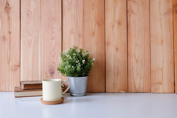 Copy space office desk books, coffee mug and plant decoration on white table and wood wall.