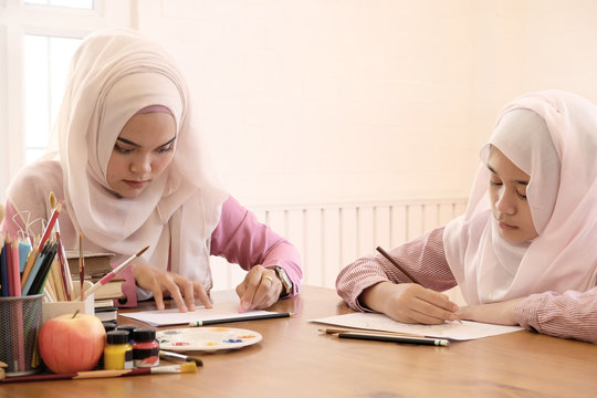 islam education concept, Adult muslim female teaching with art to learning a child girl in home.