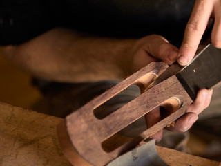 luthier makes head plate. Guitar master establishes an overlay on the head of the guitar.