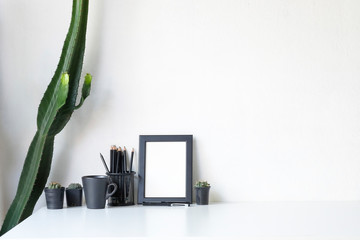 Copy space cactus, photo frame, pencil, pen and coffee on table.