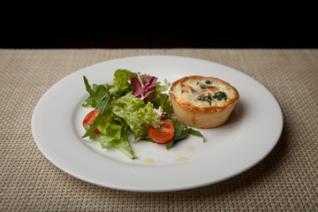 julienne in tartlet with salad and tomatoes on a white plate