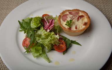 julienne in tartlet with salad and tomatoes on a white plate