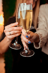 two girls clink glasses of champagne on a beautiful summer terrace. sparkling champagne glasses. close up