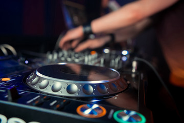Dj mixes the track in the nightclub at party. In the background laser light show