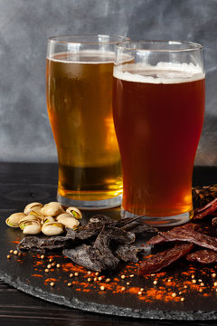 Assorted snacks, jerky on circle stone board with cold beer