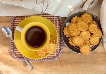 yellow cup of tea or coffee and cookies on wooden table, view from above