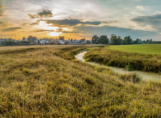 Stream on the outskirts of the city in the rays of the setting sun