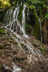 Fototapeta na wymiar Small mountain waterfall deep in the woods, preserve clean water