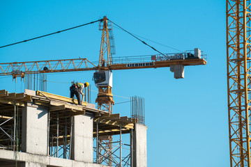Construction worker works top of the building with crane background