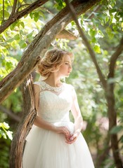 Beautiful blonde bride with stylish make-up in white dress with wedding bouquet