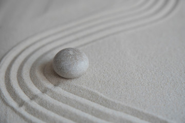 Fototapeta na wymiar Gray zen stones on the sand with wave drawings. Concept of harmony, balance and meditation, spa, massage, relax