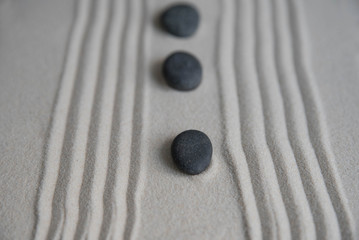 Gray zen stones on the sand with wave drawings. Concept of harmony, balance and meditation, spa, massage, relax