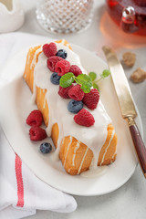 Butter vanilla cake for breakfast with glaze and fresh berries.