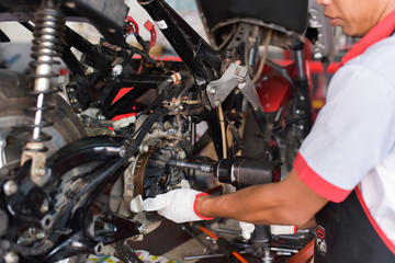 Service technicians in the drilling center of the motorcycle drum cover using the air gun to loosen the nut.