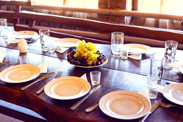 served table in the restaurant, plates, forks, knives, glasses. in the center of the ripe grapes