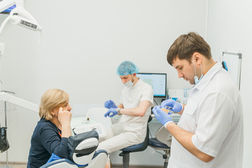 Obraz premium Doctor used microscope. Dentist is treating patient in modern dental office. Operation is carried out using cofferdam. Client is inserted and restored teeth, make denture. Orthodontist and assistant