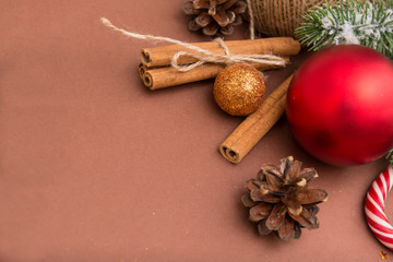 Golden, red Christmas balls, cones, cinnamon sticks, sweets on brown background
