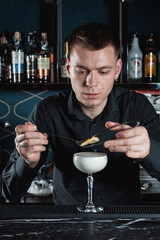 bartender making Eggnog Cocktail garnish with a lemon chips