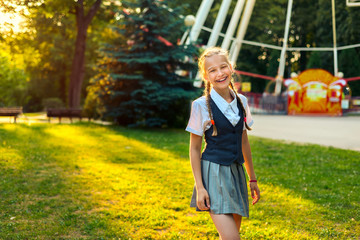 Portrait of schoolgirl in uniform laughing and rejoicing in summer in park