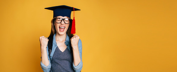 Study, education, university, college, graduate concept on banner. Happy and excited portrait of young student girl in hat of graduation isolated  - obrazy, fototapety, plakaty