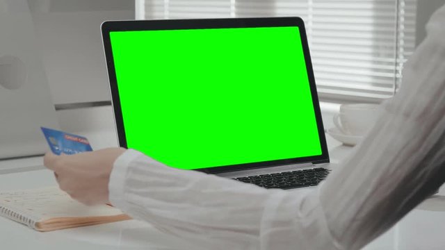 Female hands holding credit card and typing on laptop.