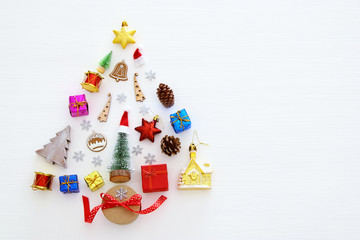 Top view image of festive decorations in shape of christmas tree over white wooden background. Flat lay.