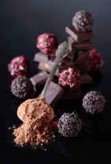 Chocolate candies, broken chocolate pieces and spoon with cocoa powder.