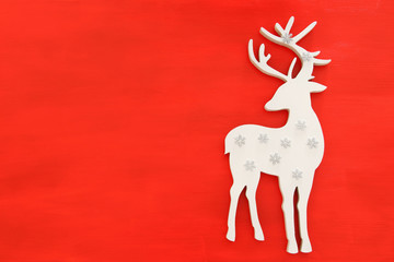 Top vie image of white wooden christmas deer over red background. Flat lay
