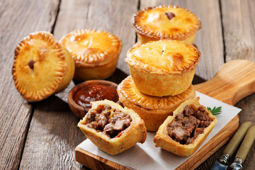 Traditional Australian Mini meat pies from shortbread dough on a wooden board over wooden...
